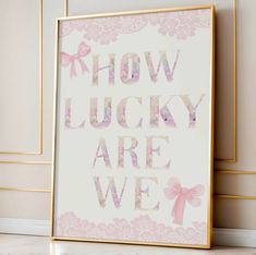 a pink and white poster with the words how lucky are we? in gold frame