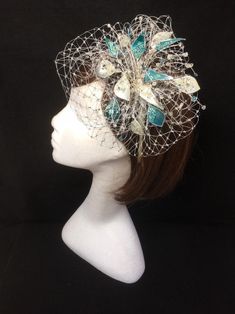 Teal blue and silver veiled fascinator perfect for the guest who wants something beautifully unique. This design is a beautiful selection of glass effect leaves and flowers clustered together amongst a fine layer of veiling and set onto a fine comfort base tiara band. As with all our designs, this piece can be made exact to the image or in any colour combination to match in with your outfit. If a specific colour is required customers can message over an image of their outfit and accessories, or Silver Headpiece For Party At Royal Ascot, Silver Headpieces For Party At Royal Ascot, Silver Headband Fascinator For Party, Silver Fascinator For Kentucky Derby Party, Silver Evening Fascinator For Kentucky Derby, Light Blue Headpiece For Royal Ascot Party, Silver Headpiece For Evening At Royal Ascot, Silver Evening Headpiece For Royal Ascot, Silver Fascinator For Evening At Kentucky Derby