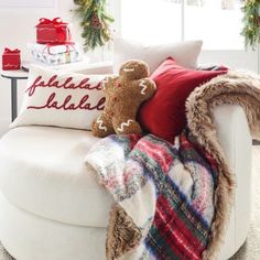 two teddy bears sitting on a white chair with christmas decorations in the corner behind them