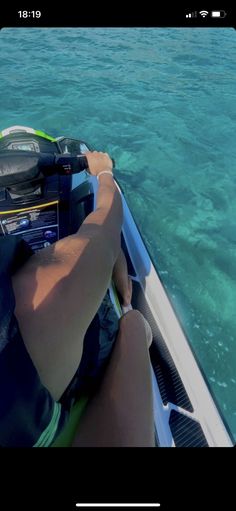 a man riding on the back of a boat in clear blue water