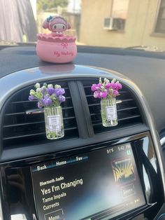 two vases filled with flowers on top of a car dashboard