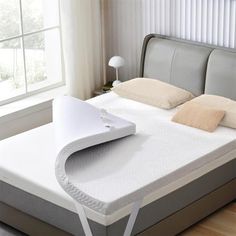 a bed with a white mattress on top of it in a room next to a window