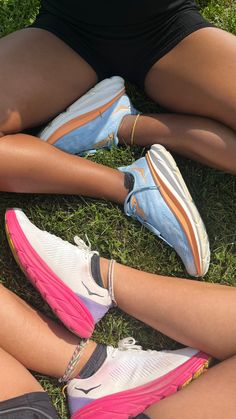 three people sitting on the grass with their feet crossed and one person wearing pink shoes