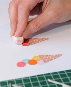 someone is making an ice cream cone craft with colored circles on the paper and glue