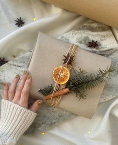 a woman's hand holding an orange slice on top of a wrapped present