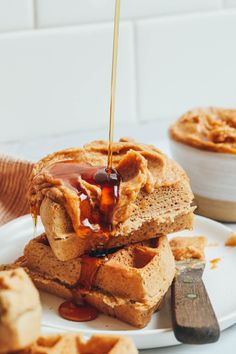 two waffles stacked on top of each other with caramel sauce being drizzled over them