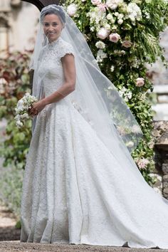 the bride in her wedding dress is walking down the street with her veil pulled back