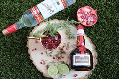 a bottle of booze next to a bowl of pomegranate on a tree stump