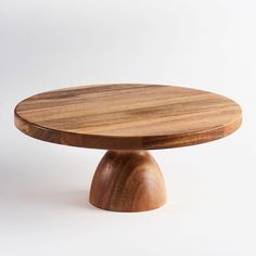 a round wooden table sitting on top of a white surface