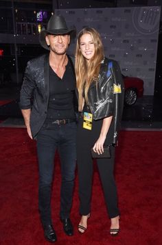 a man and woman standing next to each other on a red carpet at an event