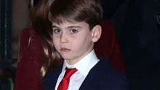 a young boy wearing a suit and red tie