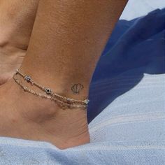 a woman's foot with a tattoo on it and a chain around the ankle