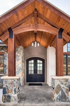 the front entrance to a home with stone pillars and wood beams on it's sides