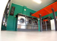 a washer and dryer in a room with green walls, two orange bars on the floor