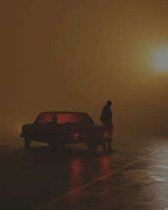 a person standing next to a car in the fog