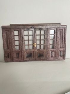 an old wooden cabinet with glass doors on the front and back sides, sitting on a white surface