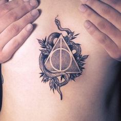 a person holding their hands in front of his chest with a harry potter tattoo on it