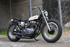 a black and white motorcycle parked next to a chain link fence