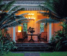 an orange house with palm trees and chairs on the front porch at night in tropical setting