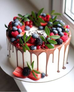 a cake with berries, raspberries and chocolate drizzled on top