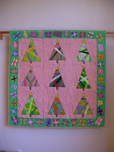 a quilted wall hanging with christmas trees on it