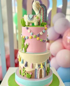 a three tiered cake with a llama on top and decorations around the edges