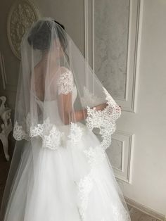 a woman in a white wedding dress with a veil on her head is looking down at the floor