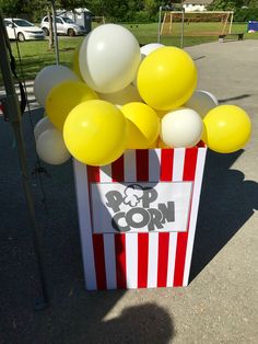 a popcorn box filled with yellow and white balloons