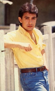 a young man leaning against a fence with his hand on the back of his shoulder