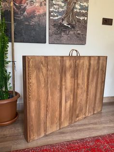 two paintings hang on the wall next to a large wooden cabinet in a living room