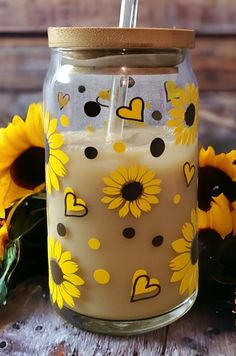 a glass jar with sunflowers painted on it and a straw in the top