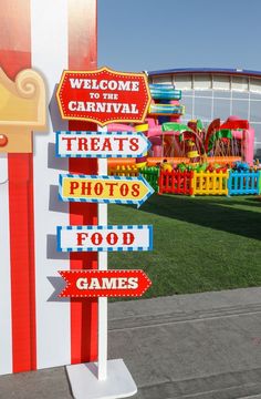 there are many signs on the pole in front of the carnival sign that says treat's photos food games