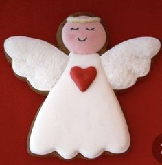 a cookie shaped like an angel with a heart in its hands on a red background