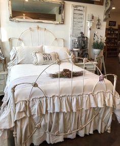 a white bed sitting inside of a bedroom next to a mirror on the side of a wall