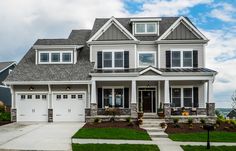 a two story house with white trim and black shutters on the front, gray shingled