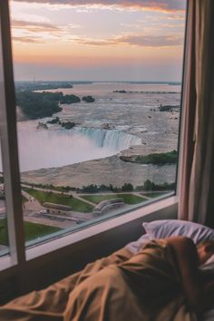 a person is laying in bed looking out the window at niagara falls and water fall