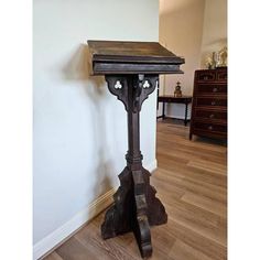 an old wooden table sitting on top of a hard wood floor next to a white wall