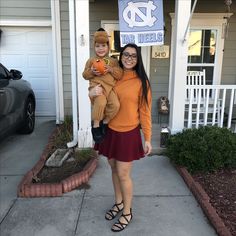 a woman holding a child in front of a house with a sign that says north carolina on it