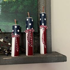 three red, white and blue candles tied with twine in front of a painting