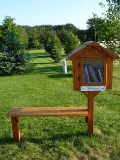 a wooden bench sitting in the middle of a field with bookshelves on it