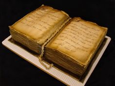 an open book with writing on it sitting on top of a white plate next to a black background