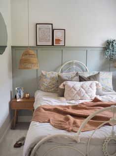 a bed with pillows and blankets on top of it next to two pictures hanging from the wall