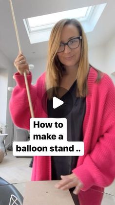 a woman holding an umbrella in her hand and standing next to a box with the words how to make a balloon stand