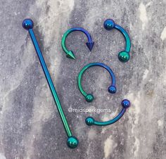 two blue and green metal hooks are laying next to each other on a gray surface