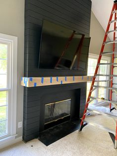 a tv mounted on top of a fireplace in a living room next to a ladder