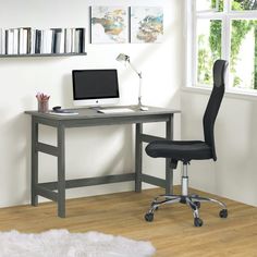 a desk with a computer on top of it in front of a window and bookshelf