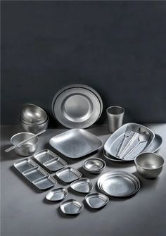 a table topped with lots of different types of dishes and silverware on top of a gray surface