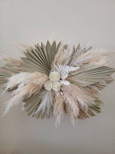 an arrangement of dried flowers and leaves on a wall