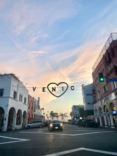 cars are driving down the street in front of buildings with a heart shaped sign above them