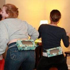 two women in jeans are playing video games with nintendo wii controllers on their back legs